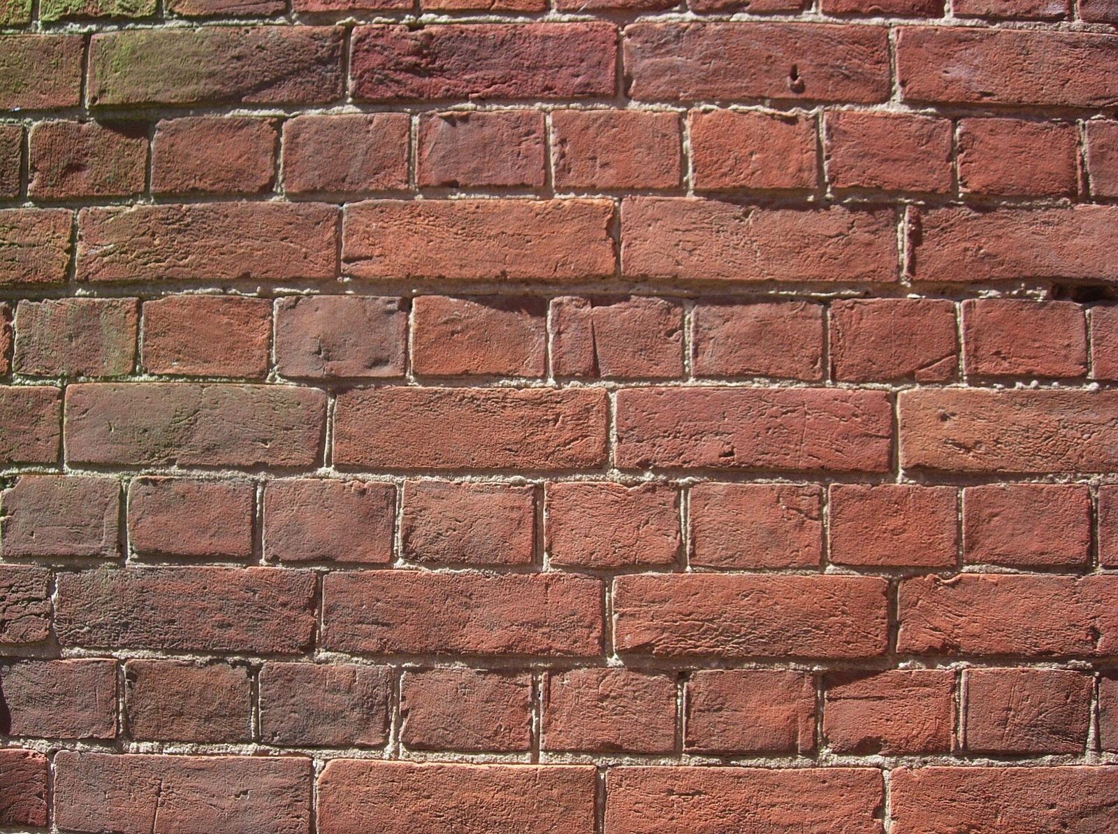 Old red brick wall with washed-out lime mortar joints